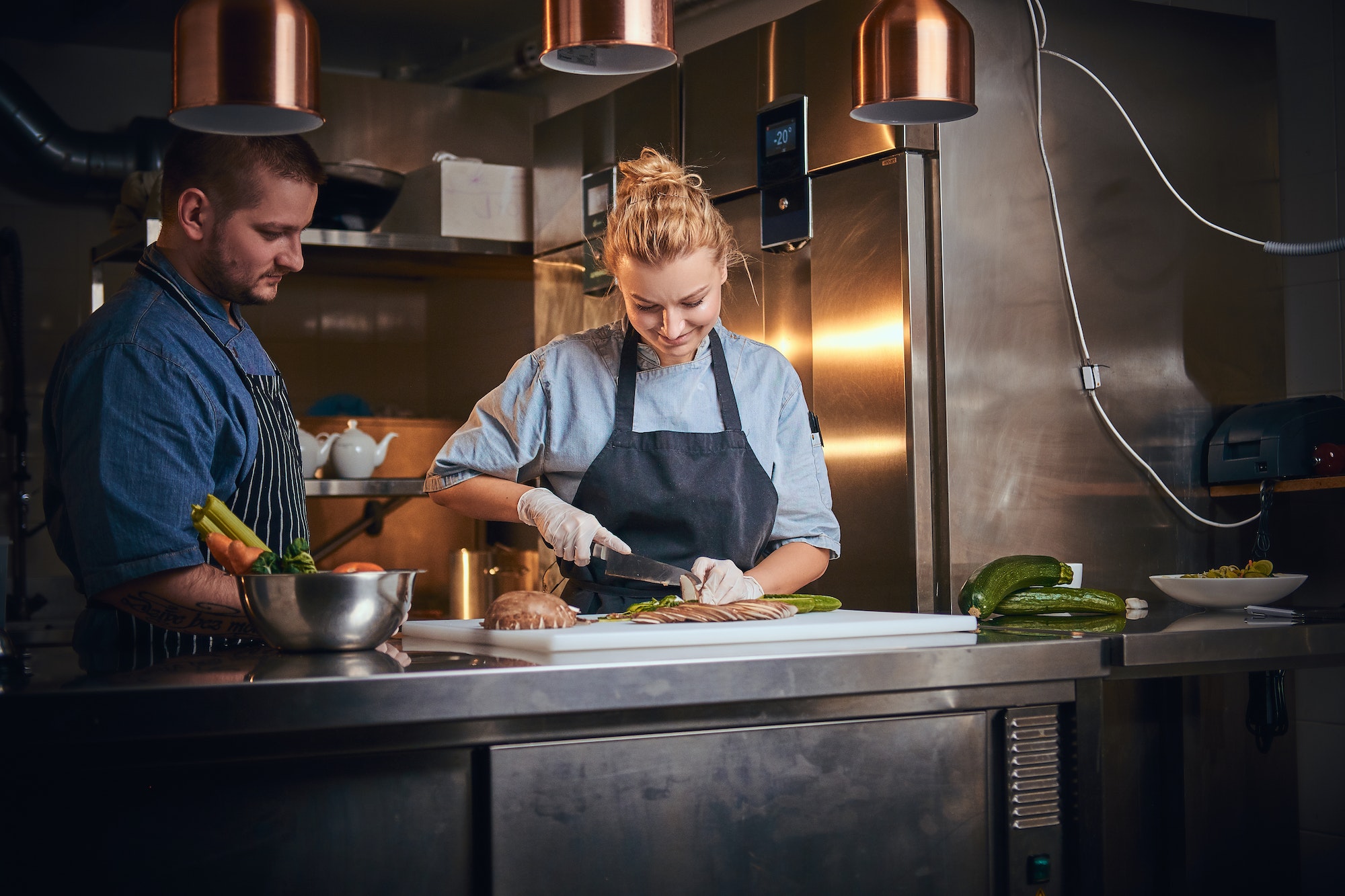 Male chef with assistant standing in a kitchen, preparing food in a luxury restaurant